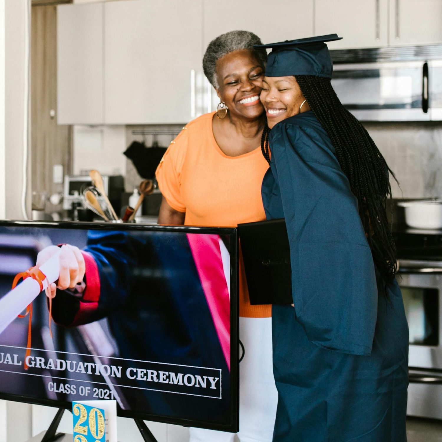 A joyful moment of virtual graduation celebration in a modern kitchen setting.